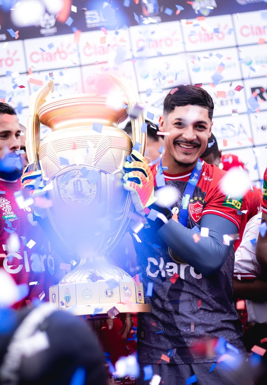 Jogador ergue a taça em meio à festa da decisão. Registro real da Super Copa Pioneer 2026.