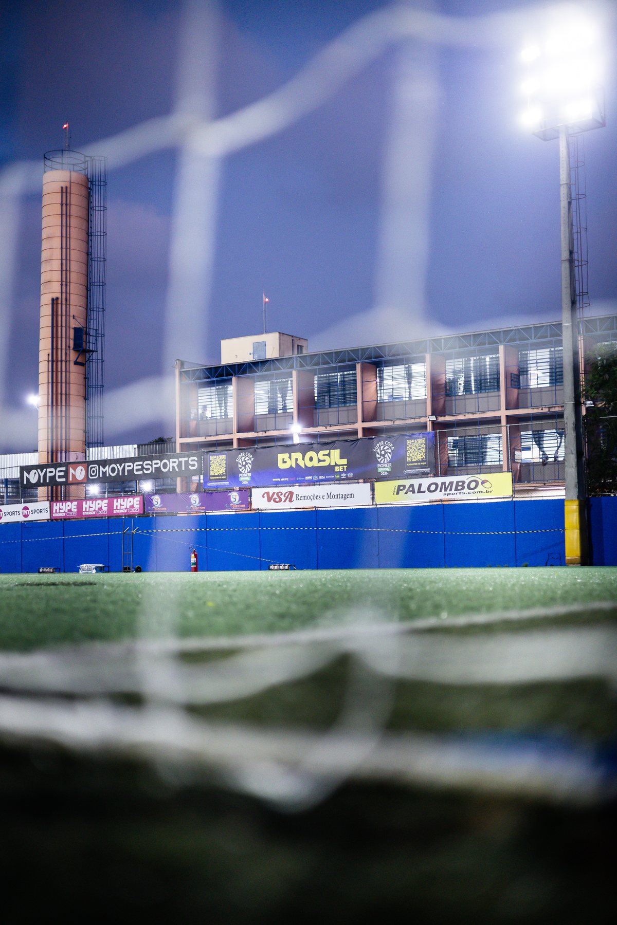 Registro fotográfico real da Super Copa Pioneer 2026 com a marca HYPE visível — Marca no estádio.